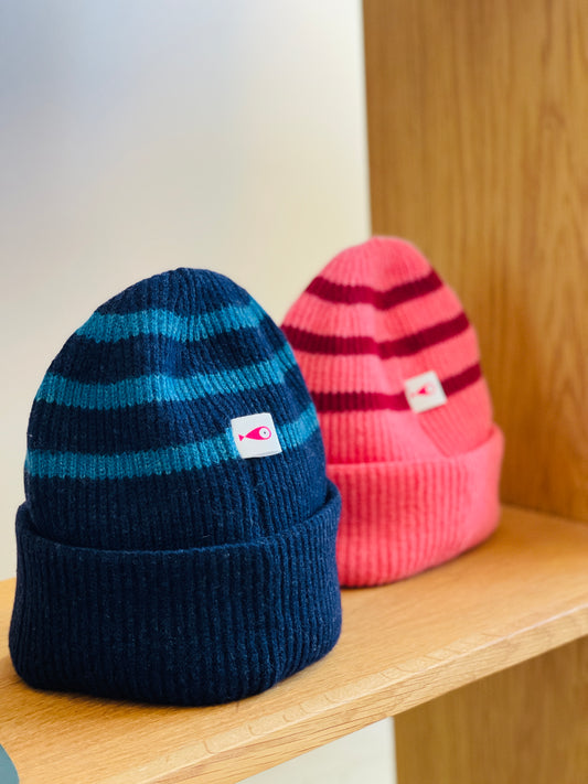 The collection of soft, colorful, and warm beanies crafted from luxurious lambswool yarn. Embrace comfort and style with these lovely accessories available in two lovely colors: Pink with red stripes and Navy blue with lighter blue stripes. Front