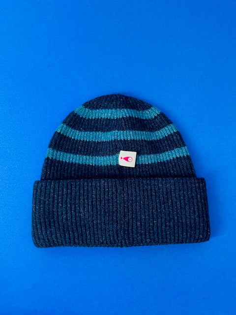 The collection of soft, colorful, and warm beanies crafted from luxurious lambswool yarn. Embrace comfort and style with these lovely accessories available in two lovely colors: Pink with red stripes and Navy blue with lighter blue stripes. Front