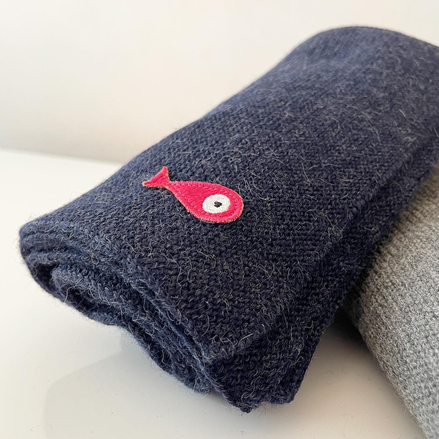 Soft, luxuriously and cozy scarfs. Knitted from a superfine alpaca yarn. Classic scarfs with a lovely feeling.  Colours : creme white, navy blue and grey  Material: 100% alpaca  Patch: pink fish  Sizes:  Navy Blue color : 2.20 cm x 22 cm  Grey color : 2.20 cm x 22 cm   Creme White color :  200 cm x 22 cm Side Front Smart casual dress code