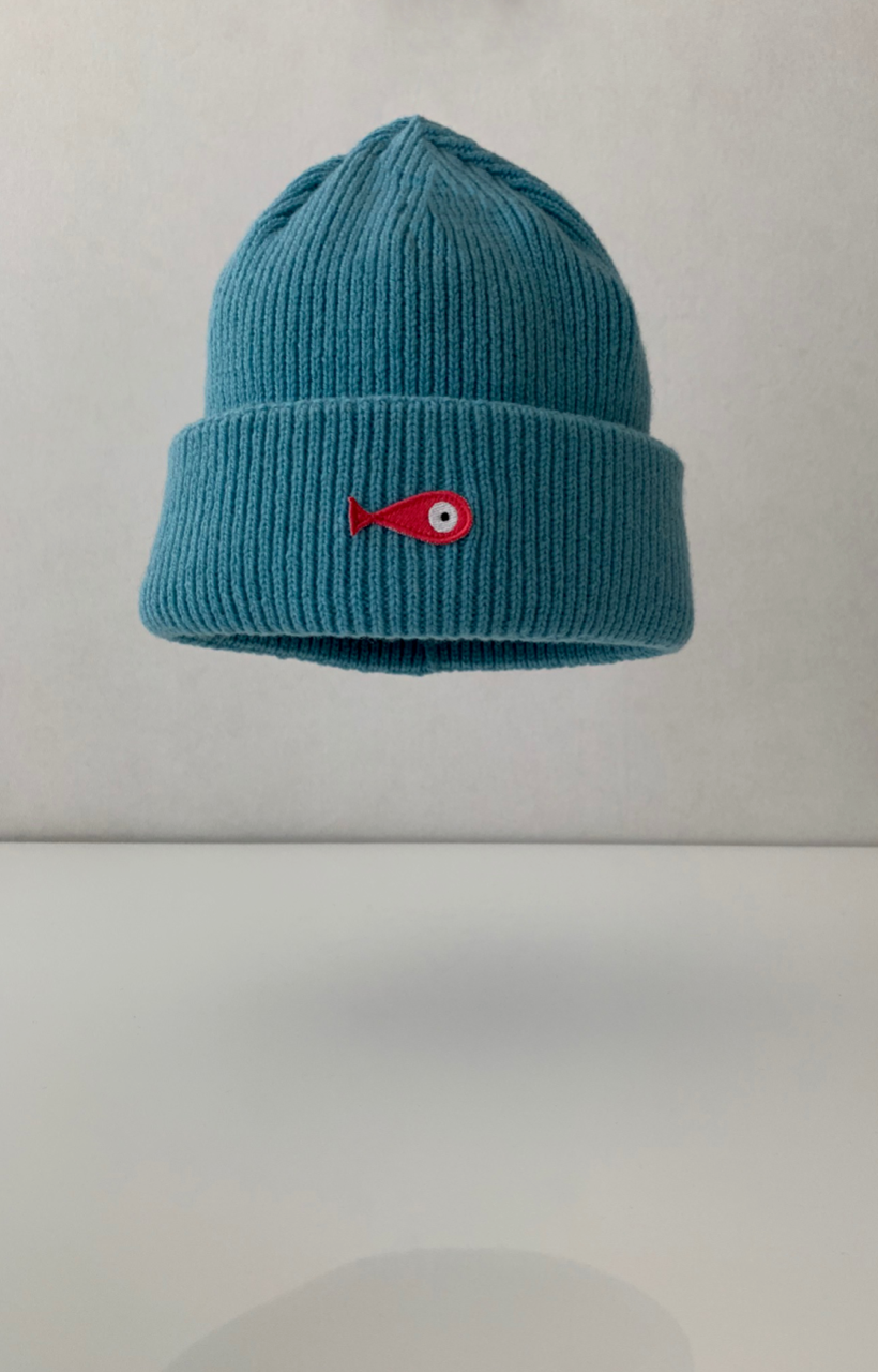 The collection of soft, colorful, and warm beanies crafted from luxurious lambswool yarn. Embrace comfort and style with these lovely accessories available in four captivating colors: Pink, Blue, Vibrant Mint, and Light Grey. Each beanie features a unique fish patch, adding a touch of charm and playfulness.  Front