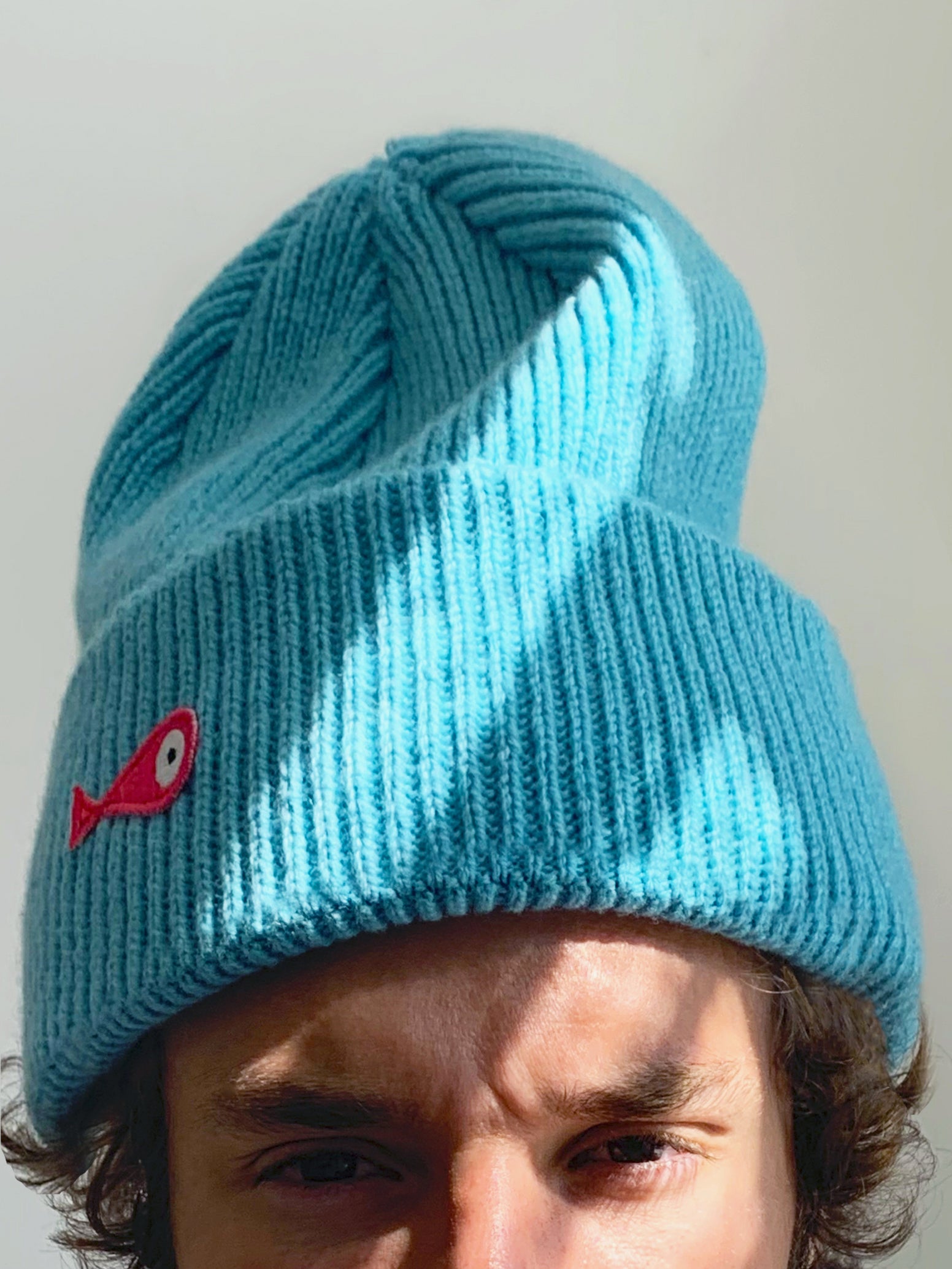 The collection of soft, colorful, and warm beanies crafted from luxurious lambswool yarn. Embrace comfort and style with these lovely accessories available in four captivating colors: Pink, Blue, Vibrant Mint, and Light Grey. Each beanie features a unique fish patch, adding a touch of charm and playfulness. Front