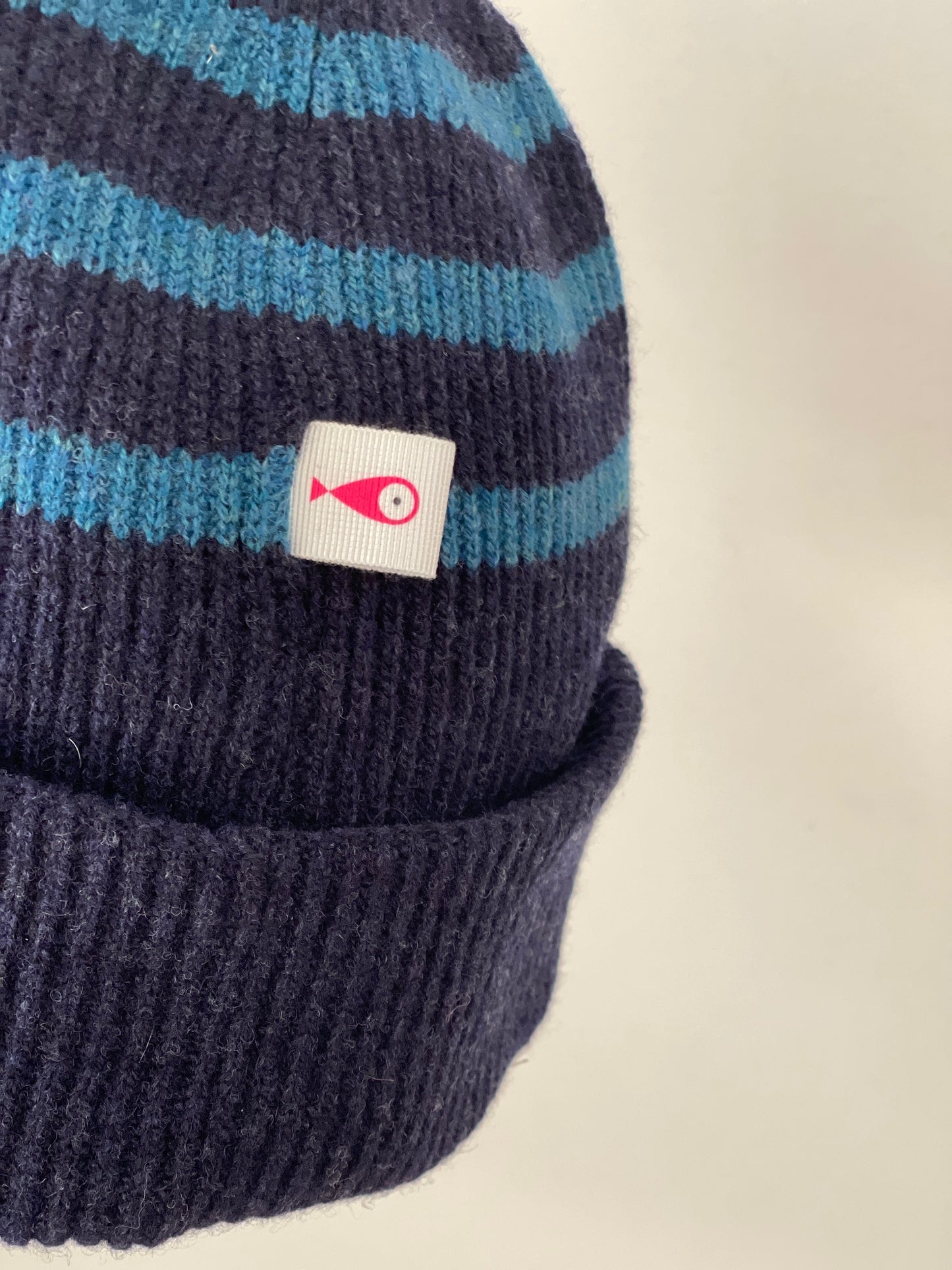 The collection of soft, colorful, and warm beanies crafted from luxurious lambswool yarn. Embrace comfort and style with these lovely accessories available in two lovely colors: Pink with red stripes and Navy blue with lighter blue stripes. Detail