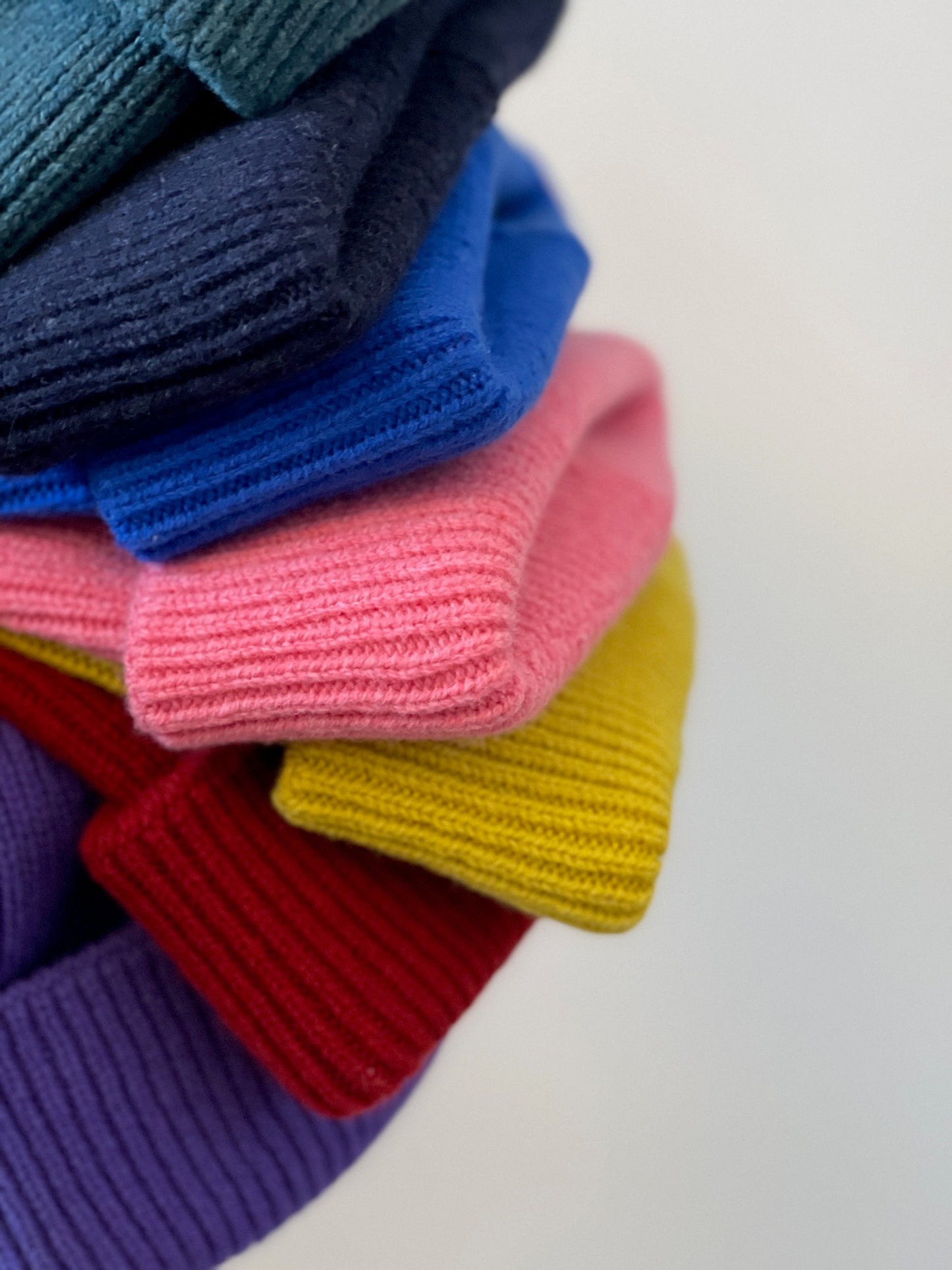 The soft, colorful, and warm kids/baby beanies crafted from luxurious lambswool yarn.   Adorned with a playful fish patch for a touch of playfulness. ( The Turquoise color features a distinctive back label. The front of the label showcases a pink fish, turn the label around, and you'll find our logo discreetly placed on the back )  Vibrant palette of seven colors – Yellow, Purple, Red, Blue, Pink, Navy Blue and Turquoise. Detail