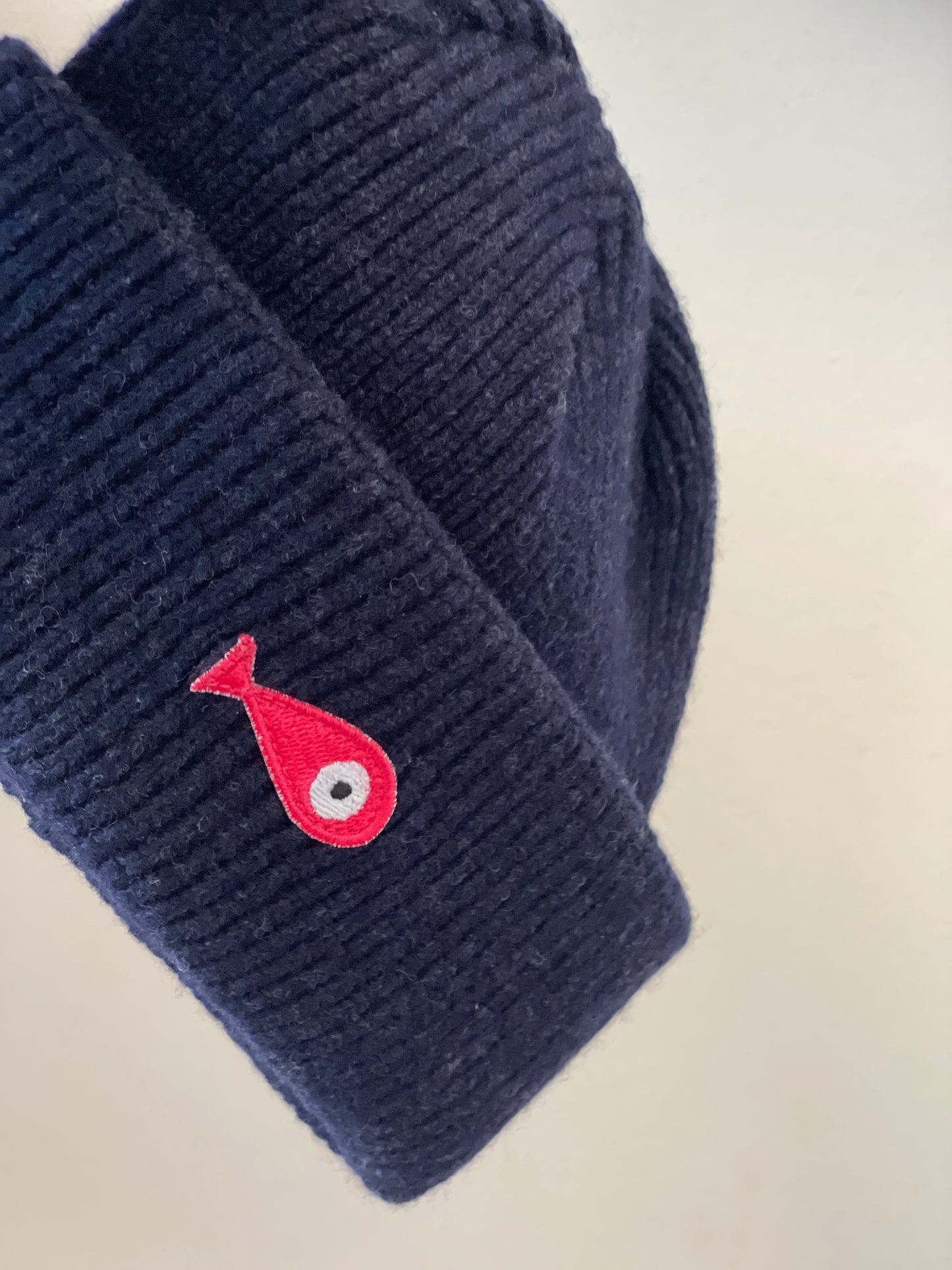 The soft, colorful, and warm kids/baby beanies crafted from luxurious lambswool yarn.   Adorned with a playful fish patch for a touch of playfulness. ( The Turquoise color features a distinctive back label. The front of the label showcases a pink fish, turn the label around, and you'll find our logo discreetly placed on the back )  Vibrant palette of seven colors – Yellow, Purple, Red, Blue, Pink, Navy Blue and Turquoise. Detail