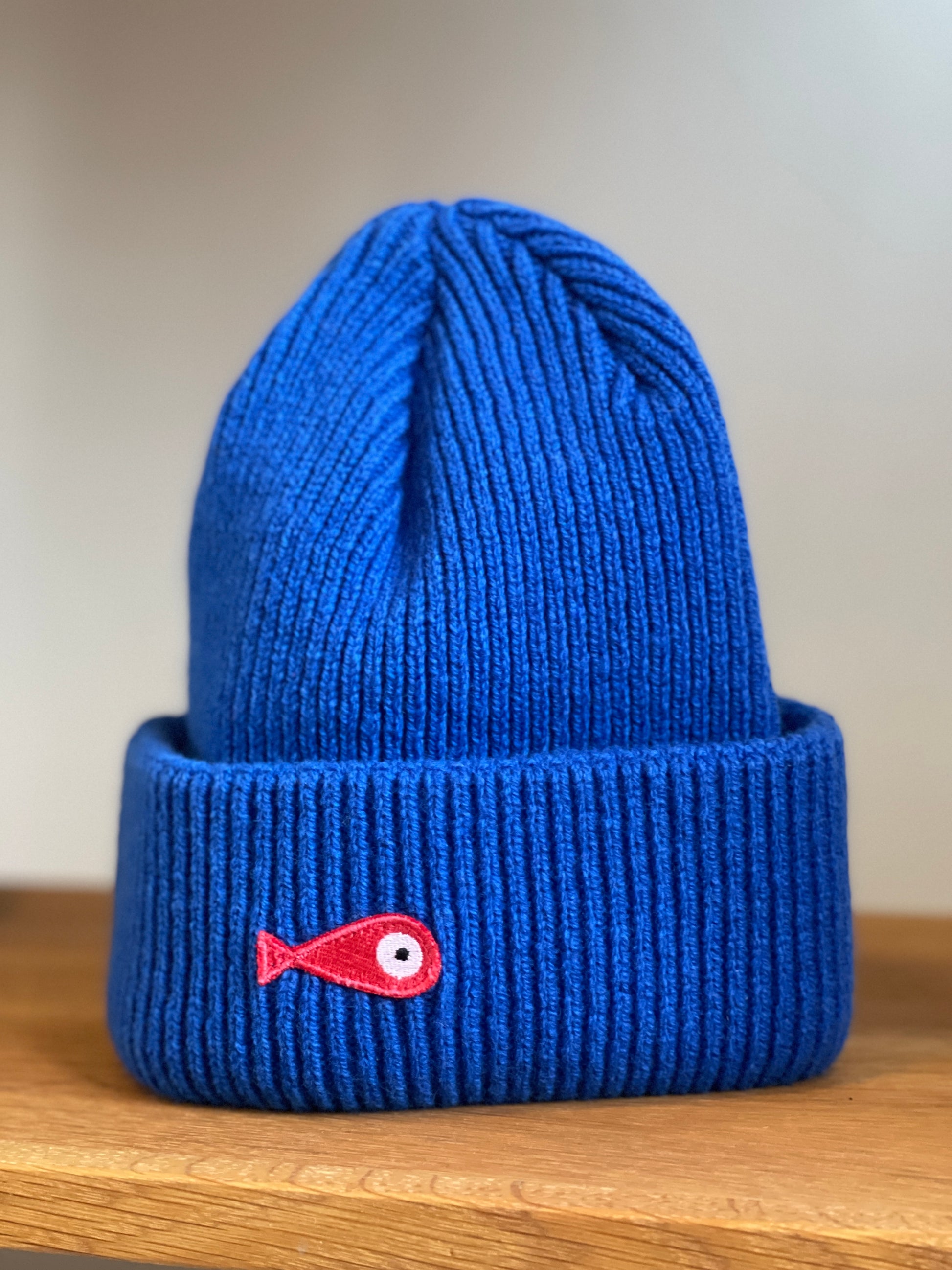 The collection of soft, colorful, and warm beanies crafted from luxurious lambswool yarn. Embrace comfort and style with these lovely accessories available in four captivating colors: Pink, Blue, Vibrant Mint, and Light Grey. Each beanie features a unique fish patch, adding a touch of charm and playfulness.  Front