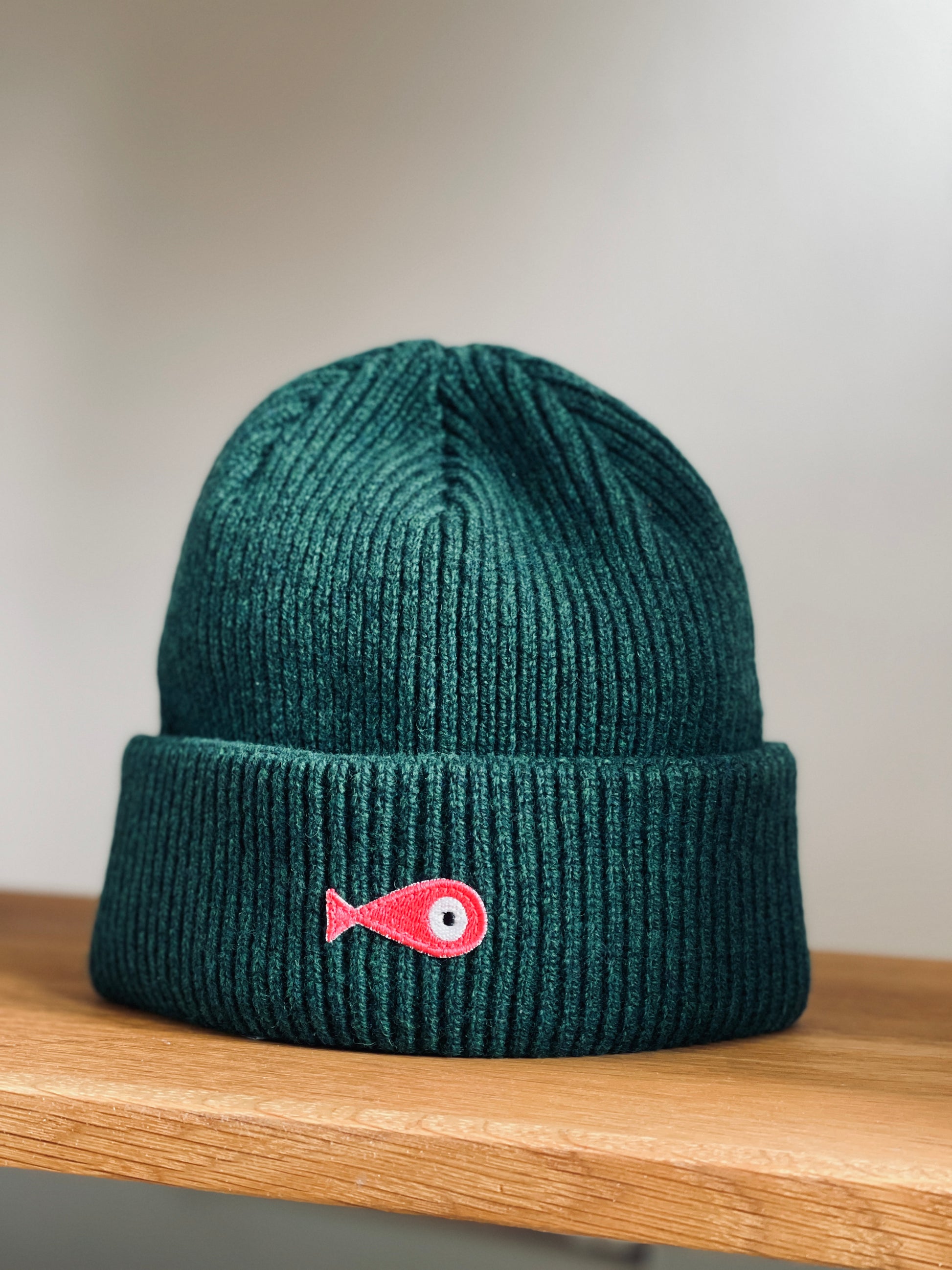 The collection of soft, colorful, and warm beanies crafted from luxurious lambswool yarn. Embrace comfort and style with these lovely accessories available in four captivating colors: Pink, Blue, Vibrant Mint, and Light Grey. Each beanie features a unique fish patch, adding a touch of charm and playfulness.  Front