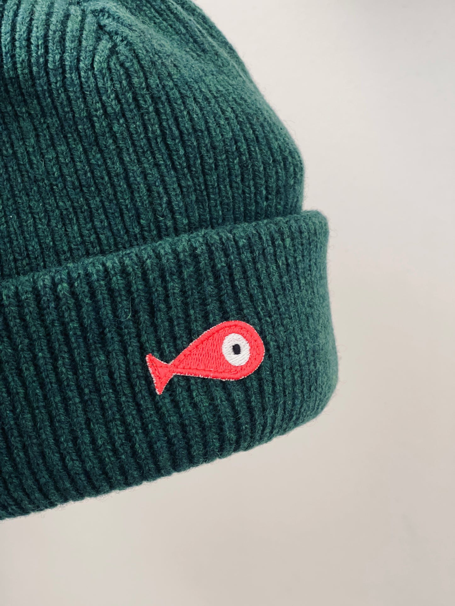 The collection of soft, colorful, and warm beanies crafted from luxurious lambswool yarn. Embrace comfort and style with these lovely accessories available in four captivating colors: Pink, Blue, Vibrant Mint, and Light Grey. Each beanie features a unique fish patch, adding a touch of charm and playfulness.  Front