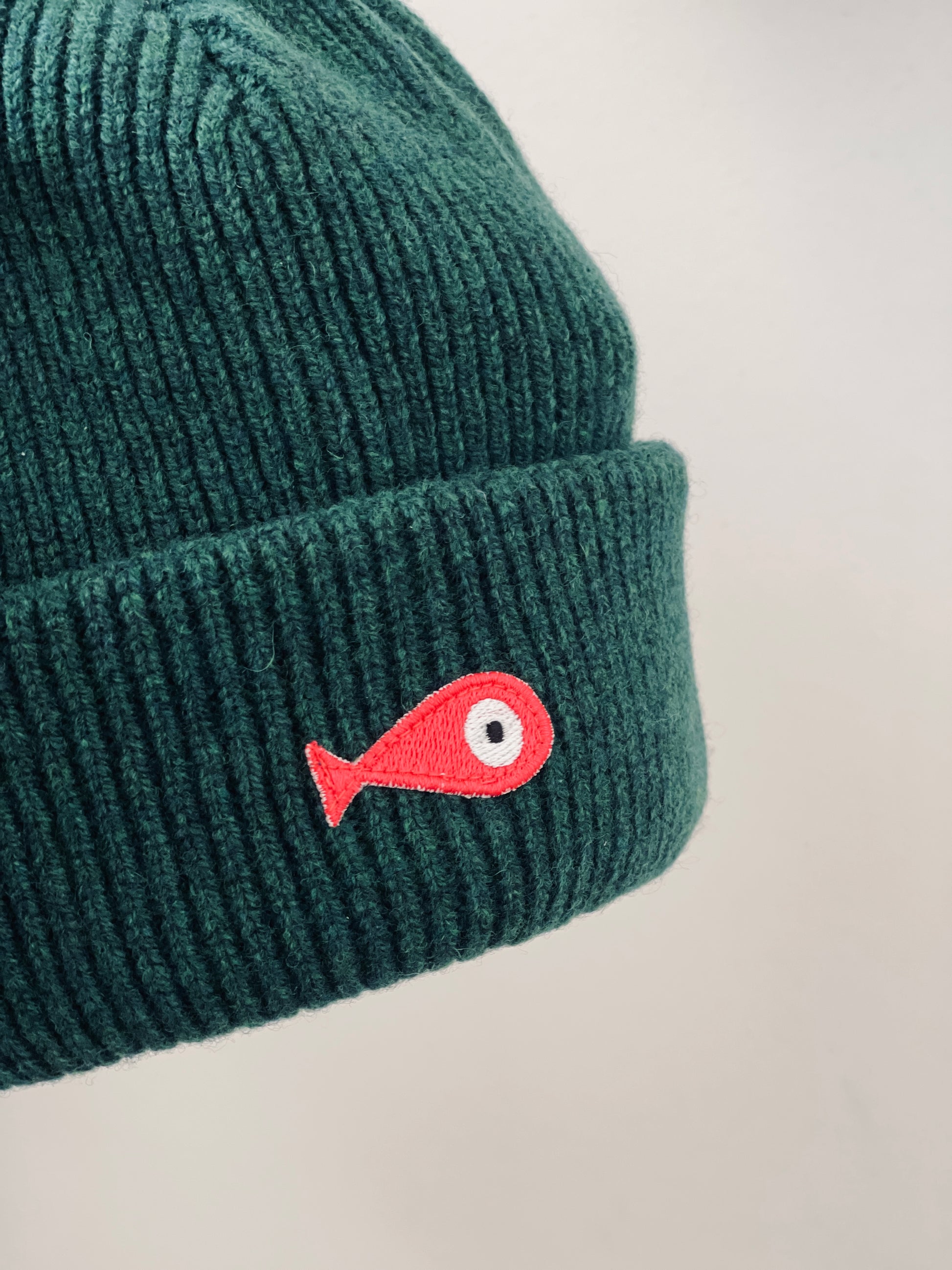 The collection of soft, colorful, and warm beanies crafted from luxurious lambswool yarn. Embrace comfort and style with these lovely accessories available in four captivating colors: Pink, Blue, Vibrant Mint, and Light Grey. Each beanie features a unique fish patch, adding a touch of charm and playfulness.  Front