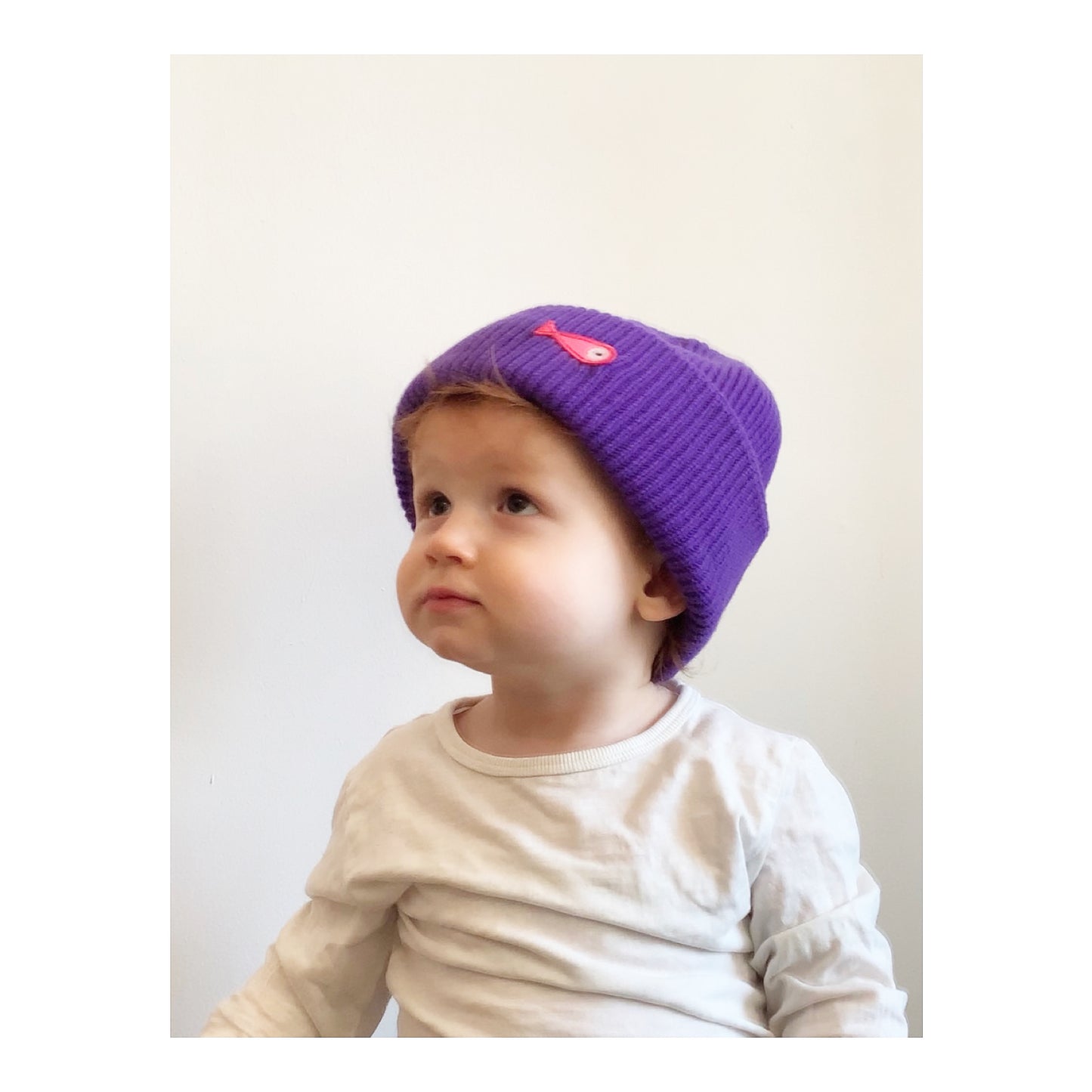 The soft, colorful, and warm kids/baby beanies crafted from luxurious lambswool yarn.   Adorned with a playful fish patch for a touch of playfulness. ( The Turquoise color features a distinctive back label. The front of the label showcases a pink fish, turn the label around, and you'll find our logo discreetly placed on the back )  Vibrant palette of seven colors – Yellow, Purple, Red, Blue, Pink, Navy Blue and Turquoise. Front