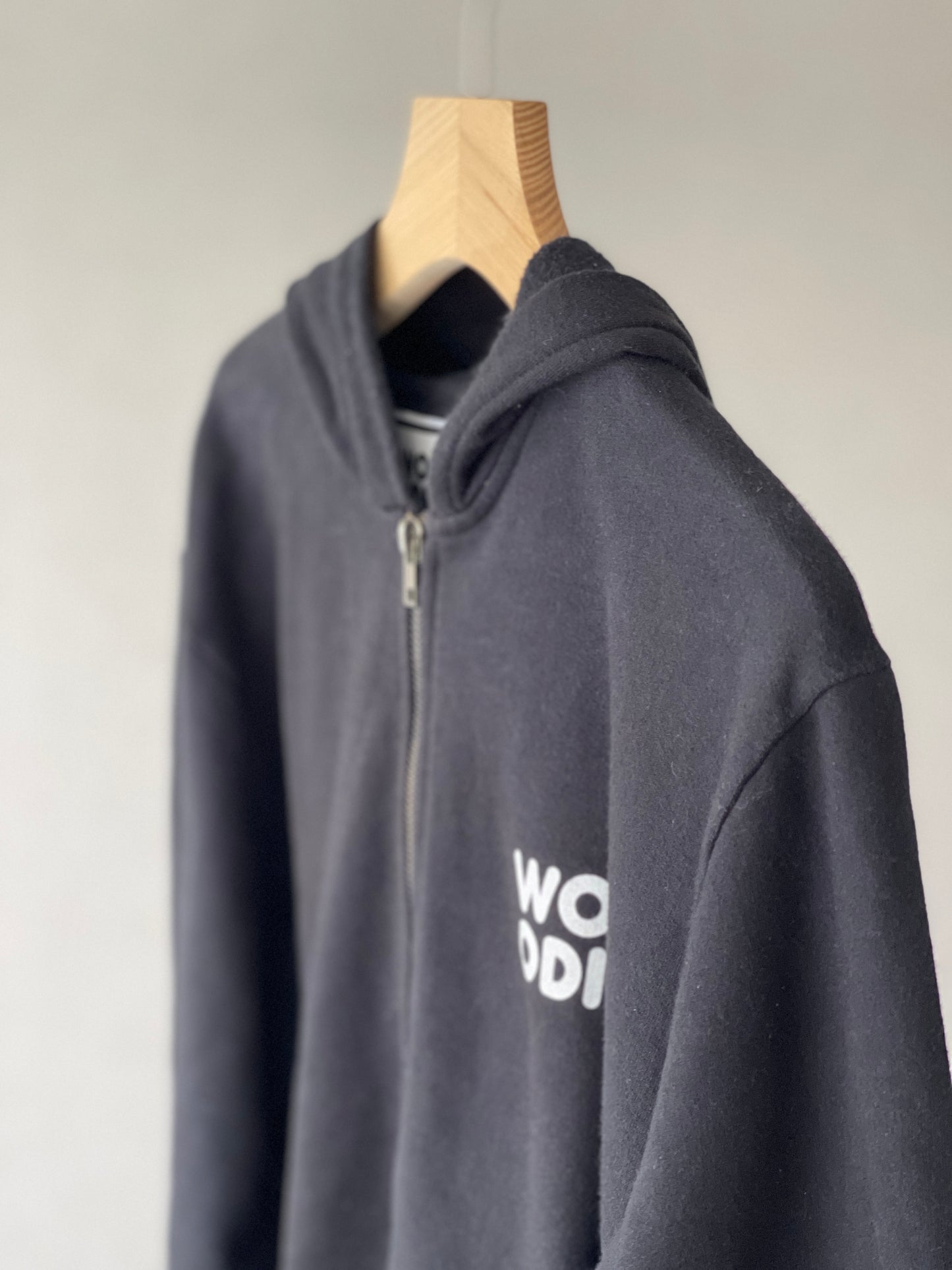 Super cozy Hoodie with a kangaroo pocket in the front with no drawstrings. Front zip closure. Crafted from 100 % superfine cotton. Raglan sleeves, ribbed trims. The pieces have a WOODI logo on front and a teddy character print on back bottom corner.  Colour: black Material: 100% cotton