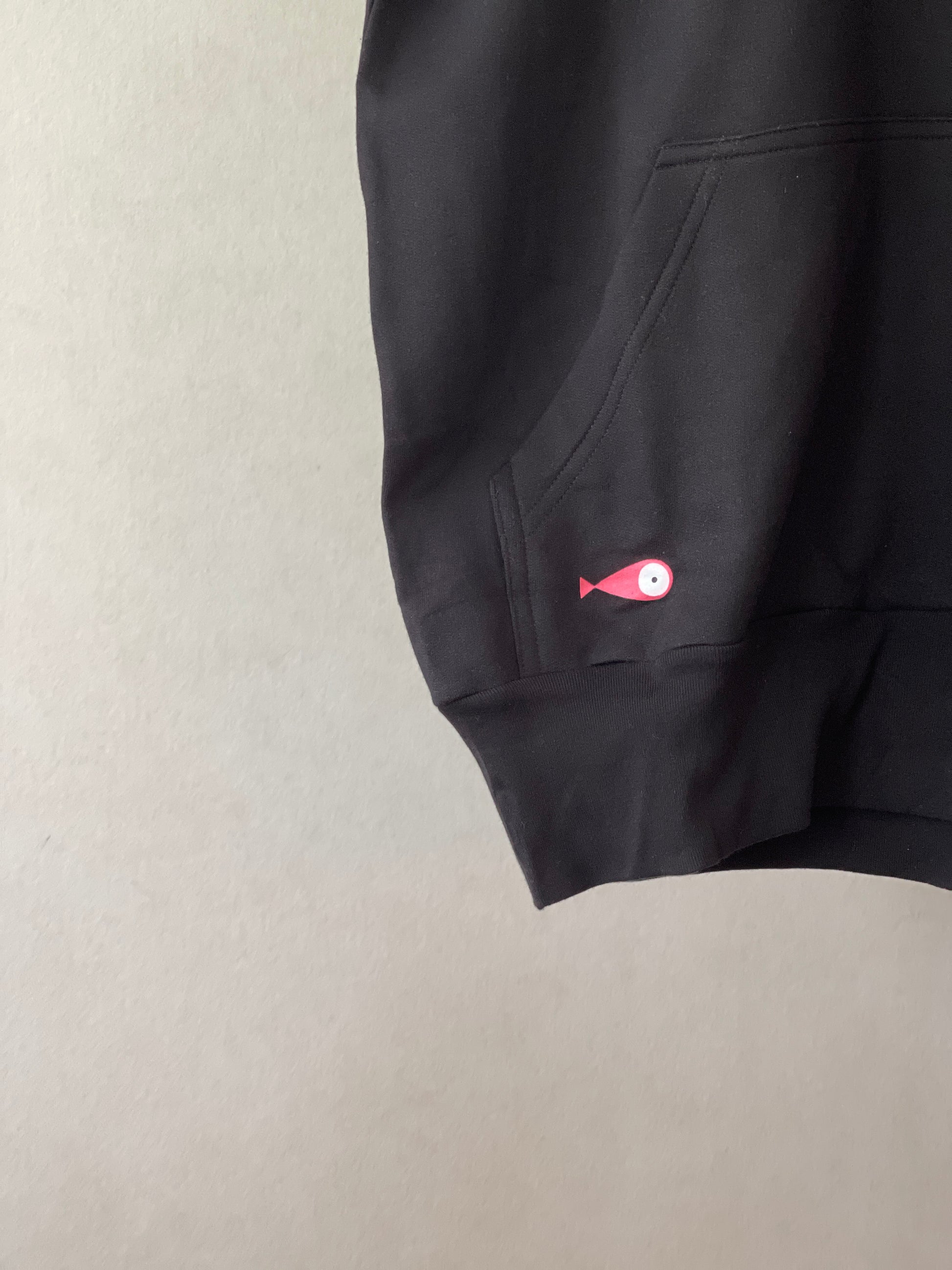 Super cozy hoodie with a kangaroo pocket in the front with no drawstrings. Crafted from 100 % superfine cotton. Raglan sleeves, ribbed trims. The pieces have a pink fish print on front left bottom corner and 4 black fishes print on right chest side.    Colour: black Material: 100% cotton