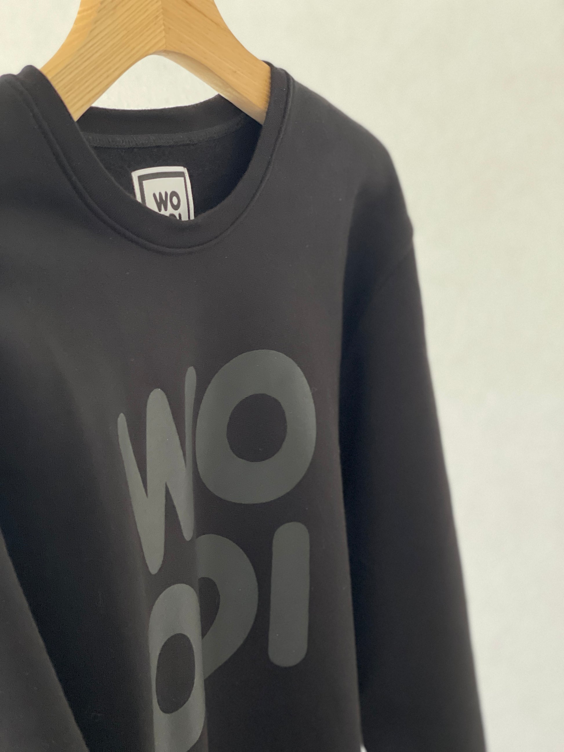 Beautifully crafted crewneck, with a classic, raglan-sleeved cut. Crafted from 100 % superfine cotton. Raglan sleeves, ribbed trims and with a double printed WOODI logo on the chest and a teddy character print on the back of the neck.  Colour: black  Material: 100% cotton