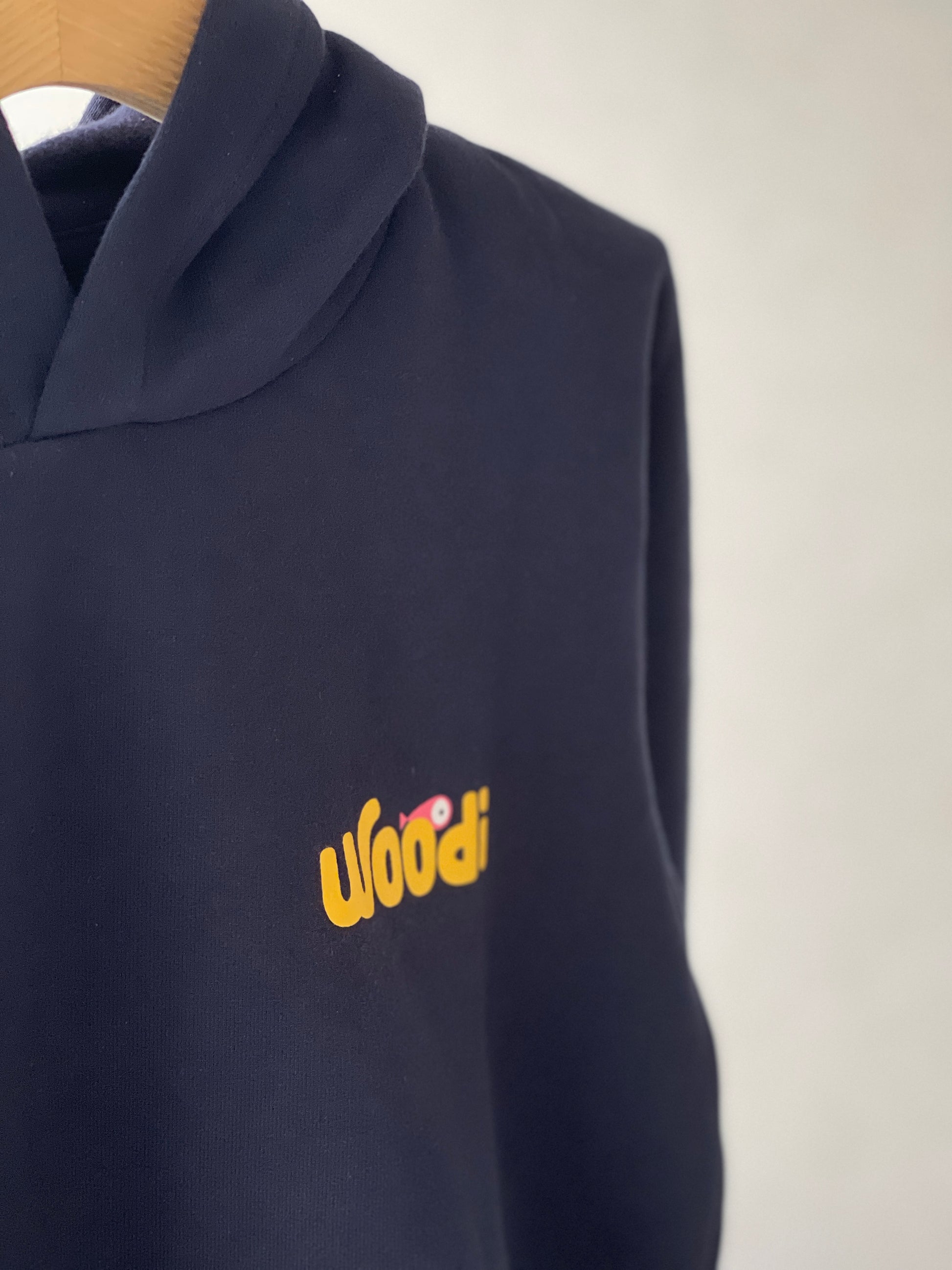Super cozy hoodie with a kangaroo pocket in the front with no drawstrings. Crafted from the finest cotton. Raglan sleeves, ribbed trims. The pieces have a WOODI swirl text and fish print in the front.  Colour: navy blue Material: 100% cotton