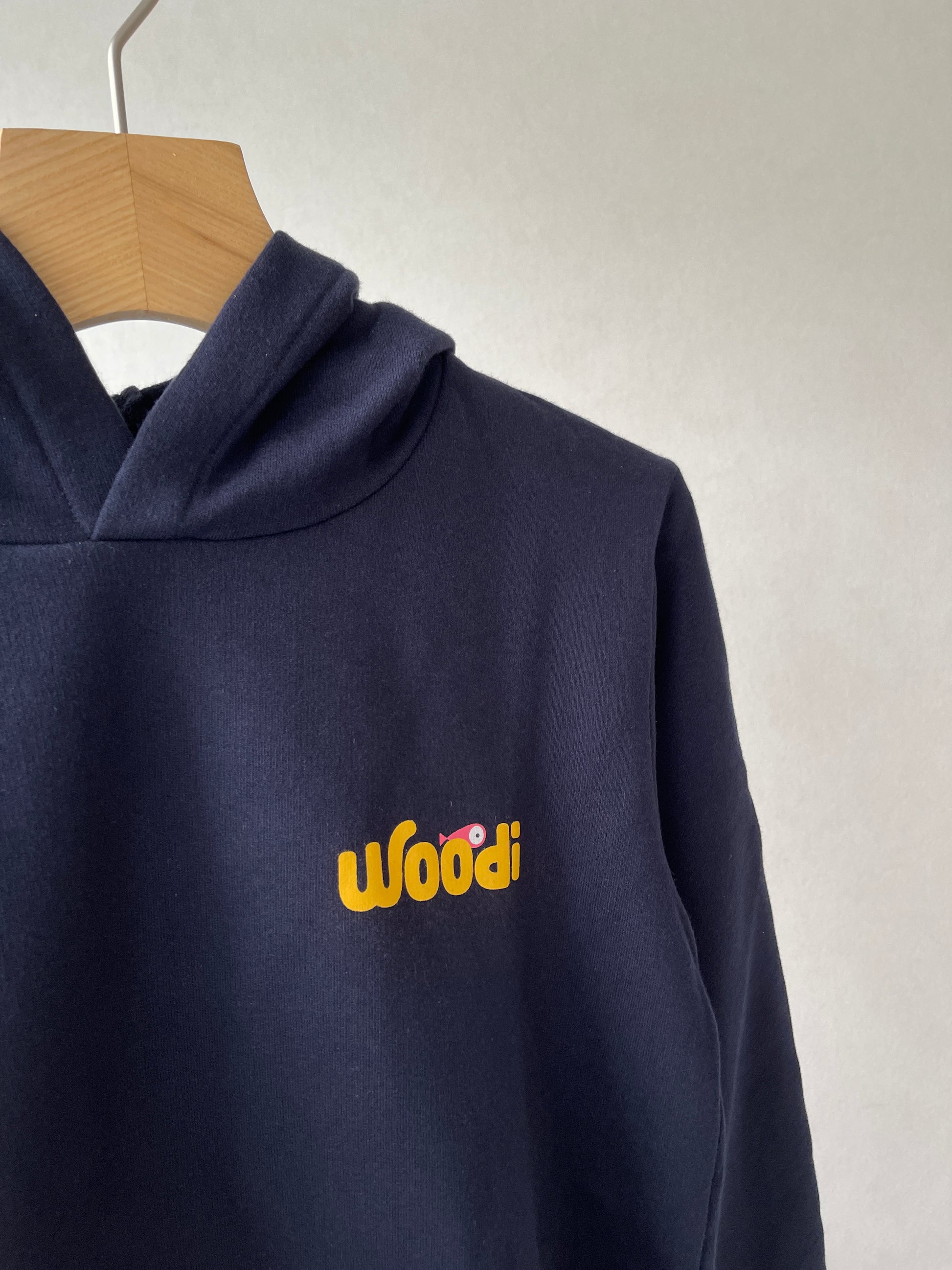 Super cozy hoodie with a kangaroo pocket in the front with no drawstrings. Crafted from the finest cotton. Raglan sleeves, ribbed trims. The pieces have a WOODI swirl text and fish print in the front.  Colour: navy blue Material: 100% cotton