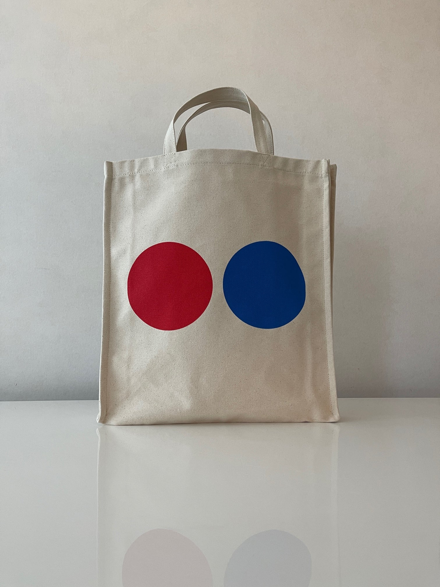 Lovely tote bag crafted from a organic cotton canvas.  Short handles. A great companion that will never let you down. Perfect for the beach, school, shopping and weekend trips. Red & blue dots on both sides of the tote bag. WOODI logo print inside Size : 39 cm x 35 cm 