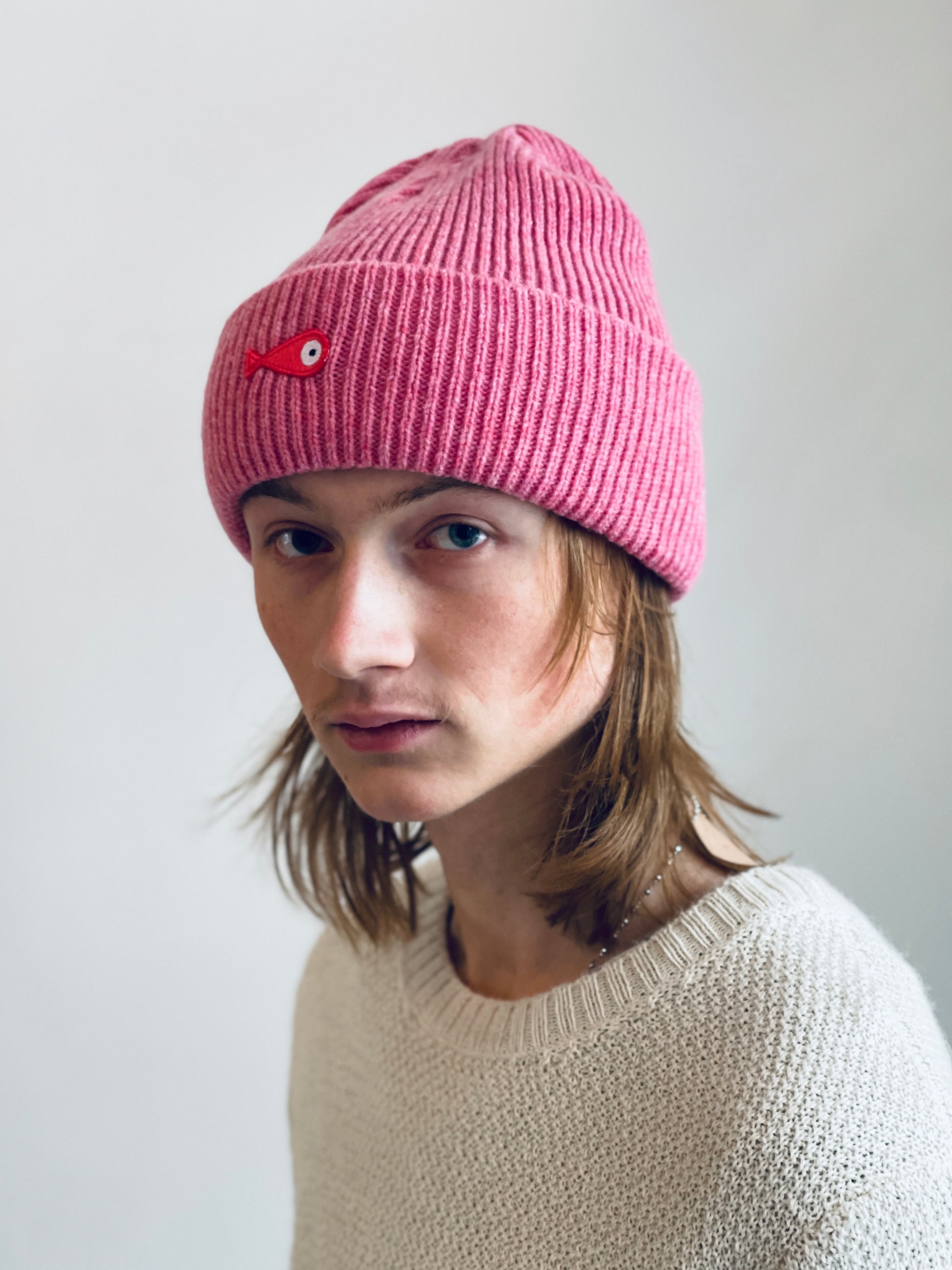 The collection of soft, colorful, and warm beanies crafted from luxurious lambswool yarn. Embrace comfort and style with these lovely accessories available in four captivating colors: Pink, Blue, Vibrant Mint, and Light Grey. Each beanie features a unique fish patch, adding a touch of charm and playfulness.  Front