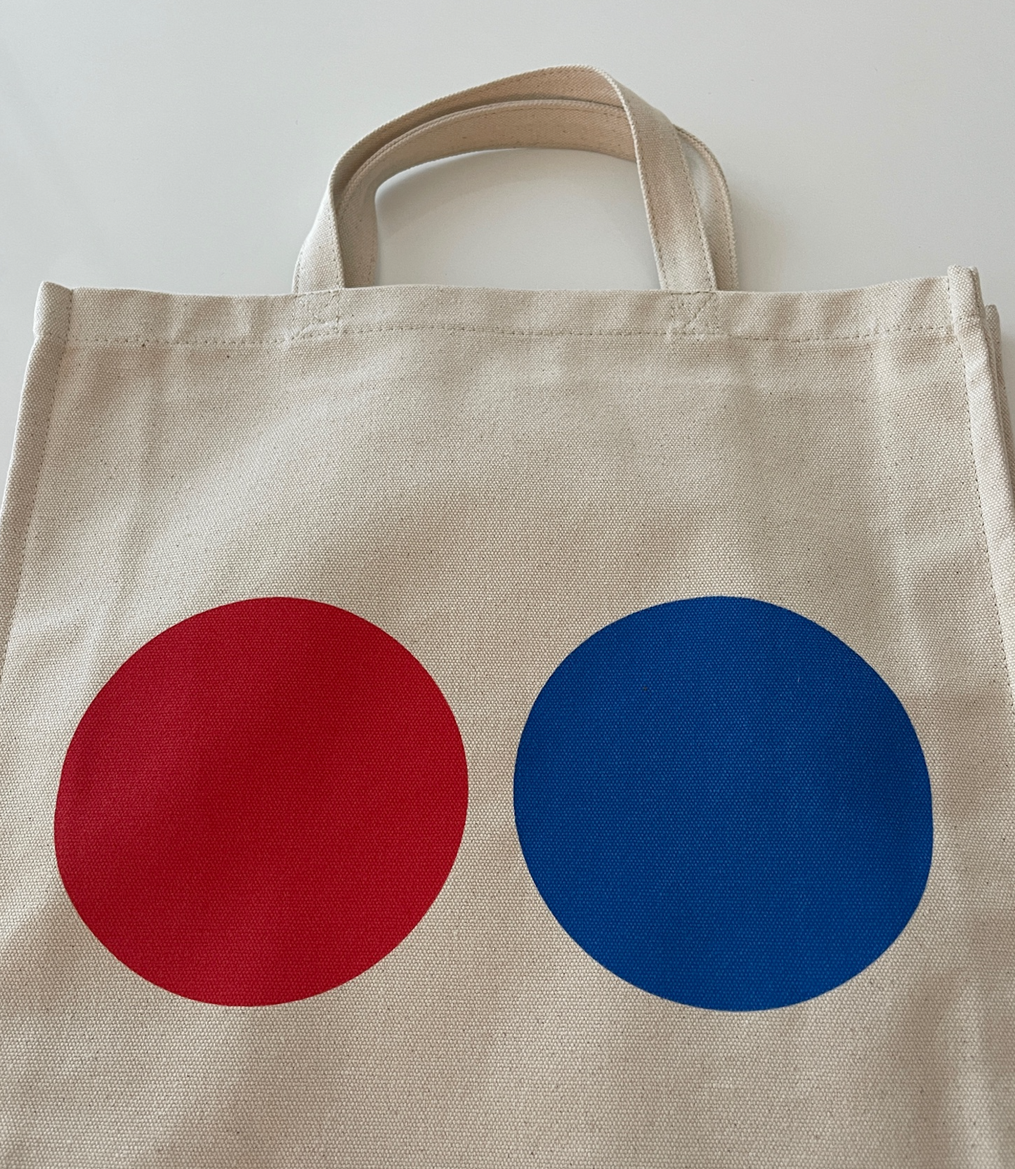 Lovely tote bag crafted from a organic cotton canvas.  Short handles. A great companion that will never let you down. Perfect for the beach, school, shopping and weekend trips. Red & blue dots on both sides of the tote bag. WOODI logo print inside Size : 39 cm x 35 cm 